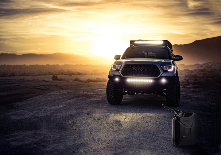 Black Wavian 20L NATO jerry can on the ground in front of a Toyota Tacoma at sunset